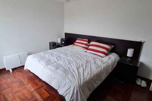 a bedroom with a bed with two red and white pillows at Naturaleza y árboles San Isidro in Lima