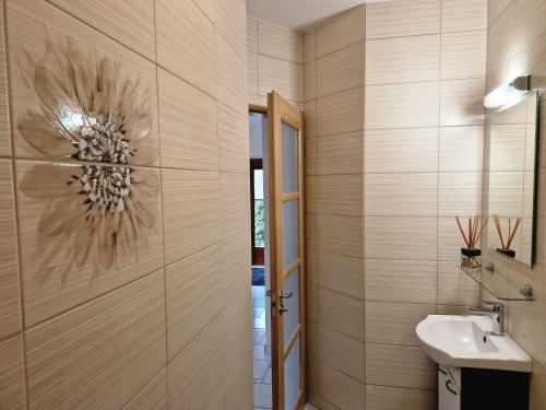 uma casa de banho com um lavatório e uma parede com uma flor em Linos Apartamentai em Druskininkai
