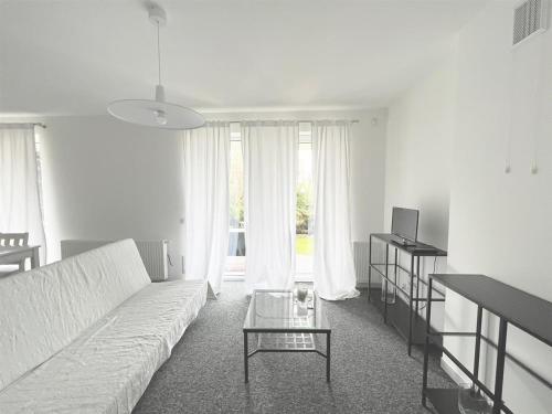 ein Wohnzimmer mit einem weißen Sofa und einem Tisch in der Unterkunft Apartamenty Orłowo in Gdynia