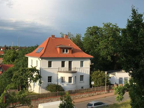 a white house with an orange roof on a street at Ferienwohnung im Blauen Haus in Bad Suderode