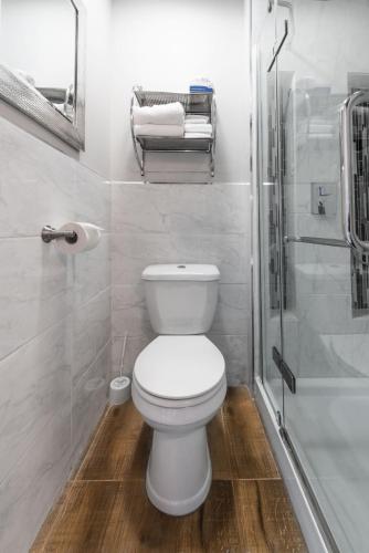 a white bathroom with a toilet and a shower at Le Chateau de Pierre in Quebec City