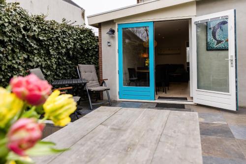 a patio with a blue door and a table with flowers at Strand 11 in Callantsoog