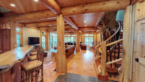 a large living room with wooden ceilings and a staircase at Oneida Lodge North in Cooperstown