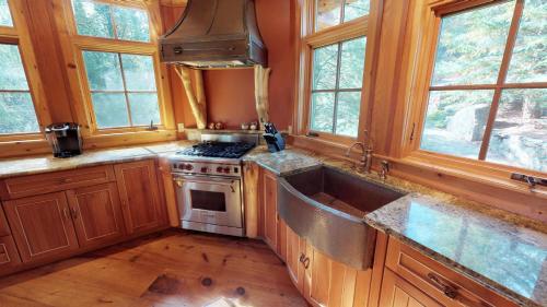 a kitchen with a sink and a stove and windows at Cayuga Lodge South in Cooperstown