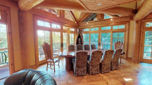 a dining room with a table and chairs and windows at Cayuga Lodge South in Cooperstown