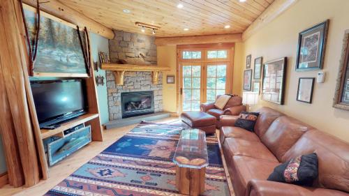 a living room with a couch and a tv and a fireplace at Cayuga Lodge South in Cooperstown