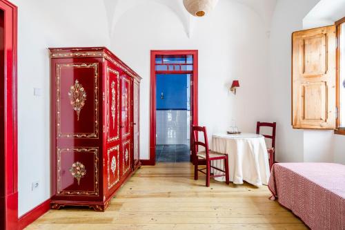 a bedroom with a red dresser and a table and a room at Casa Garcia in Amareleja