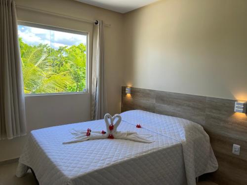 a bedroom with a white bed with a window at Pousada Donna Maraka in Porto De Galinhas