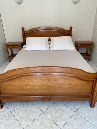 a wooden bed with white sheets and two night stands at Le gîte de Charline in Selles-sur-Cher