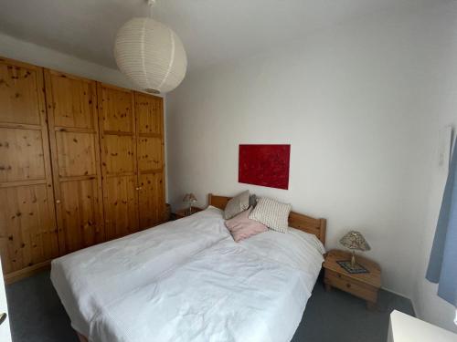 Schlafzimmer mit einem großen weißen Bett und Holzschränken in der Unterkunft Ferienwohnung im Blauen Haus in Bad Suderode