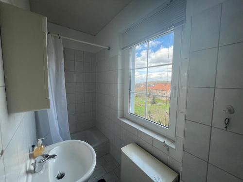 a white bathroom with a sink and a window at Ferienwohnung im Blauen Haus in Bad Suderode