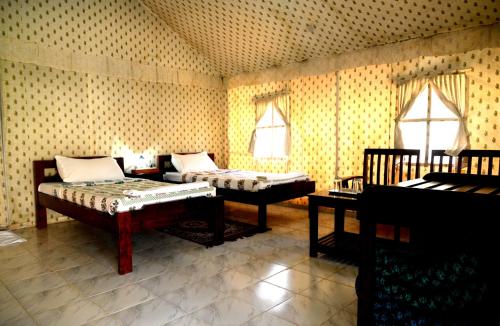 Habitación con 2 camas, mesa y ventanas. en Cattle Inn - Luxury Tents Pushkar, en Pushkar