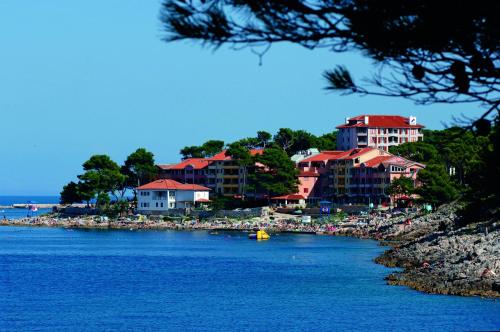 a group of buildings on a beach next to the water at Apartments Punta in Veli Lošinj