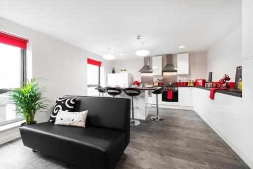 a living room with a black couch and a kitchen at Yugo Explore - Arofan House in Cardiff