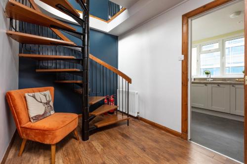 an orange chair in a living room with a spiral staircase at The Edinburgh Rooftop Terrace in Edinburgh