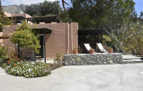 a house with a stone wall and flowers at Anemos - Holiday Beach Houses in Keratokampos