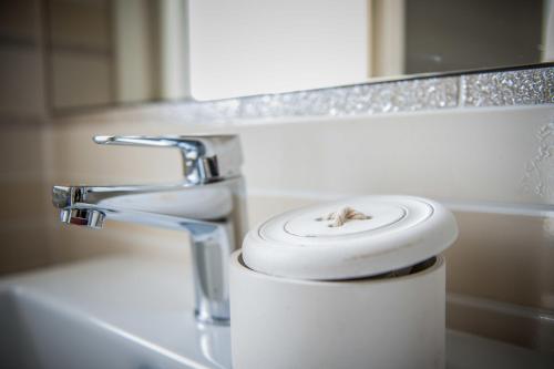 a toothbrush in a bucket next to a bathroom sink at Locanda Corte Montioni in Lazise