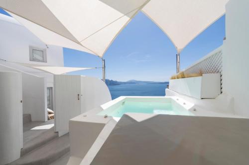 a white house with a swimming pool and a window at Delta Suites in Oia