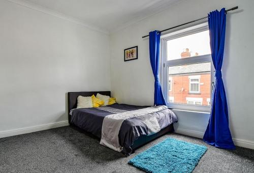 a bedroom with a bed and a window with blue curtains at Friendly Stockport in Stockport