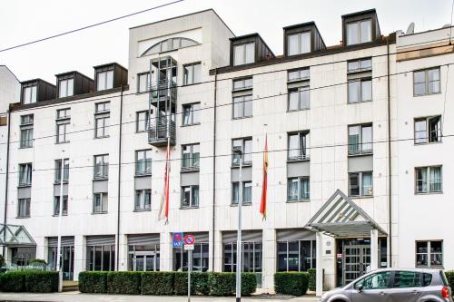 un grand bâtiment blanc avec des drapeaux rouges devant lui dans l'établissement Valemi Stay - Selfservice, à Düsseldorf