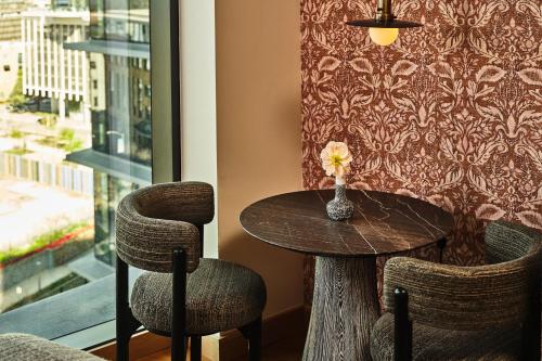 a table and chairs in a room with a window at Austin Proper Hotel, a Member of Design Hotels in Austin