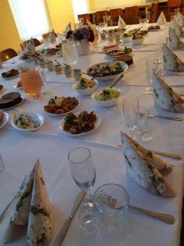 una mesa larga con platos de comida y copas de vino en Kriaunų bendruomenės Svečių namai, en Gipenai