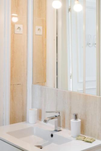 une salle de bain avec un lavabo et un miroir dans l'établissement Magnifique appartement avec cheminée sur la plage, à Trouville-sur-Mer