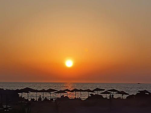 - un coucher de soleil sur l'océan avec des parasols sur la plage dans l'établissement Agrabeli Cottage in Platanos, à Plátanos
