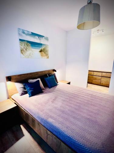 a bedroom with a large bed with blue pillows at Apartament „Nova Polana” Kołobrzeg Polanki Park in Kołobrzeg