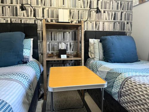 two beds and a table in a room with book shelves at Woodbriar in Penmaen-mawr