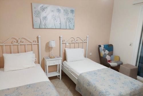 カシオピにあるPanayota Apartmentsのベッドルーム1室(ベッド2台、椅子、絵画付)