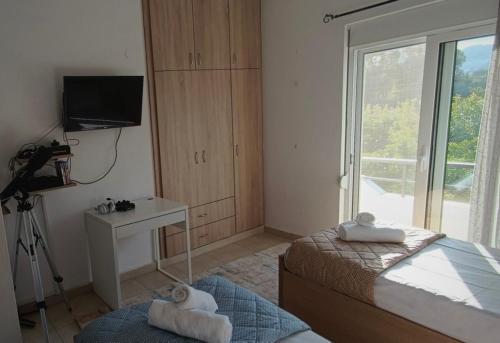 1 dormitorio con 1 cama, TV y ventana en Bouvegio Apartments Giorgos en Afántou