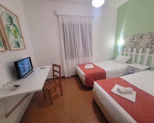 a hotel room with two beds and a desk with a television at Sleep and Go in Santana in Nature B&B in Santana