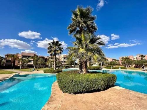una palmera sentada junto a una piscina en Super appartement familial avec piscine à Prestigia Marrakech, en Marrakech