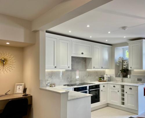 a white kitchen with white cabinets and a sink at Heather Mere Cottage, Bowness-on-Windermere in Bowness-on-Windermere