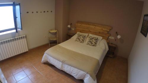 Un dormitorio con una cama en una habitación con ventana. en Castell de Ceuró. Hotel Rural, en 
