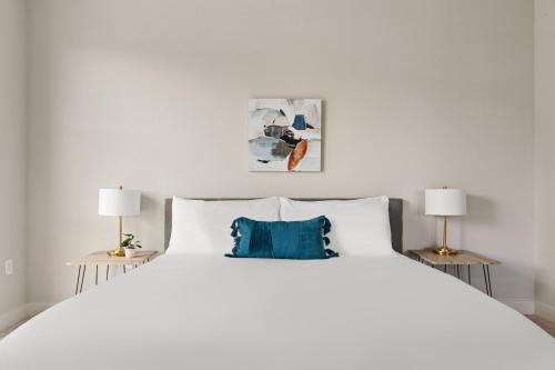 a bedroom with a large white bed with two lamps at Kasa RiNo Denver in Denver