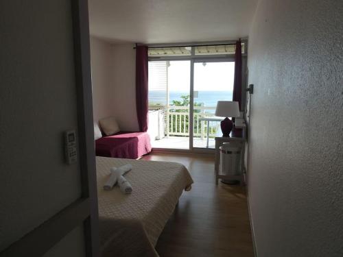 a room with a bed and a window with a view of the ocean at Appartement terrasse vue mer et piscine in Le Diamant