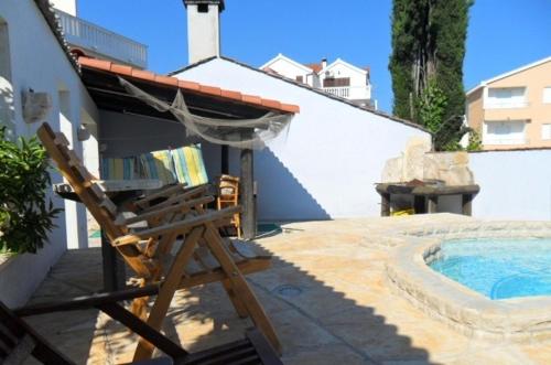 una sedia in legno seduta accanto alla piscina di Apartments Kafadar a Trogir