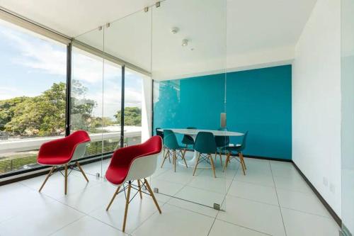 a dining room with a table and red chairs at Rooftop Jacuzzi and city view in San José