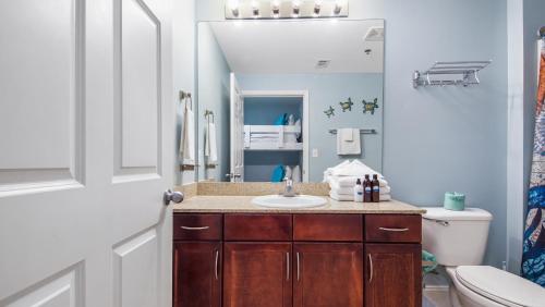 a bathroom with a sink and a toilet and a mirror at The Turtle Nest at Laketown Wharf #414 by Nautical Properties in Panama City Beach