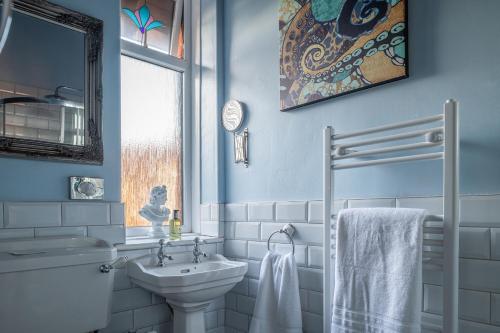 a blue bathroom with a sink and a toilet at The House on Cabbell in Cromer