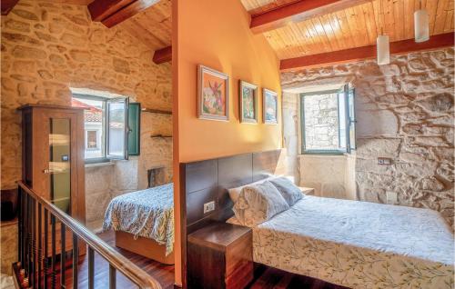 a bedroom with two beds in a stone wall at Awesome Home In Muros With Wifi And 2 Bedrooms in Muros