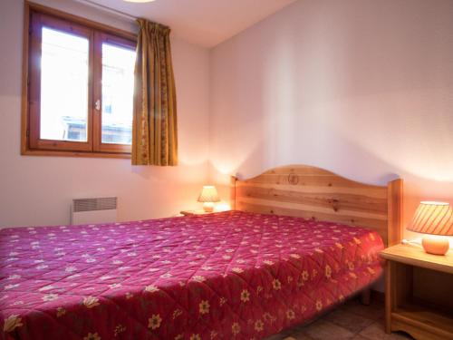 um quarto com uma cama com uma colcha vermelha e uma janela em Appartement Aussois, 3 pièces, 6 personnes - FR-1-508-95 em Aussois