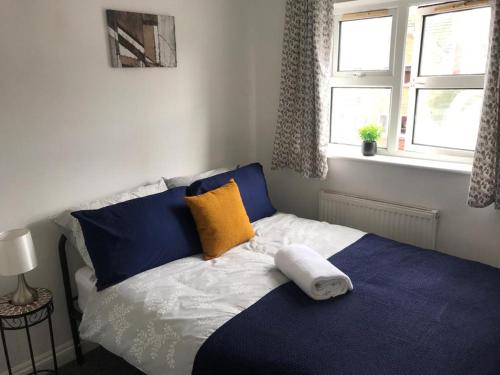 Schlafzimmer mit einem Bett mit blauen und gelben Kissen in der Unterkunft Accomodation for contractors & professionals 3 bed house with parking in Lighthorne