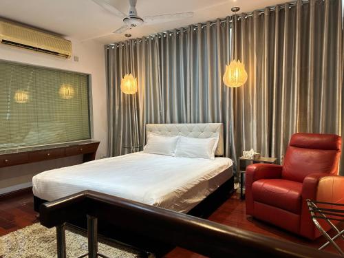 1 dormitorio con 1 cama y 1 silla roja en Contemporary Heights Hotel and Apartments, en Dhaka