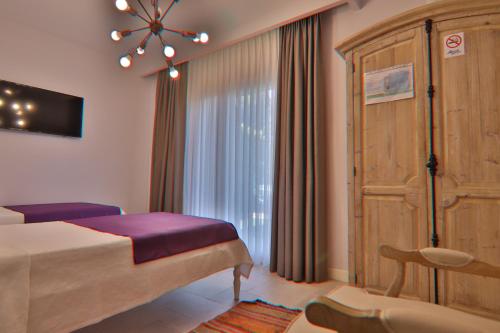 a bedroom with a bed and a large window at Alacaat Otel in Alaçatı