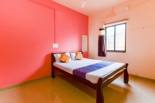 Panhāla的住宿－SPOT ON Hotel Diamond Lodging And Boarding，一间卧室配有一张红色墙壁的床