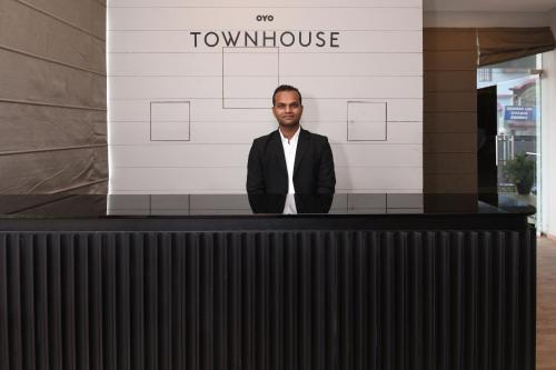 CharbaghSuper Townhouse Function Inn Near Chaudhary Charan Singh International Airport的站在大楼前柜台后面的人