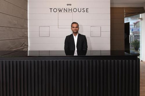 a man standing behind a counter in front of a building at Townhouse Function Inn Near Chaudhary Charan Singh International Airport in Charbagh